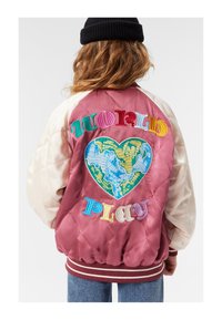 Giacca bomber trapuntata in bordeaux e crema, caratterizzata da un testo ricamato multicolore "world" e "play" sopra una mappa del mondo a forma di cuore.