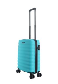 Turquoise hard-shell suitcase with ridged texture, black retractable handle, four black spinner wheels, and side TSA lock.