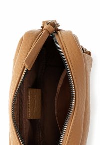 Brązowa skórzana torebka na ramię o teksturowanym wykończeniu, zamknięciu na zamek błyskawiczny oraz wnętrzu wyłożonym brązową tkaniną. Kompaktowy design o schludnym kształcie.