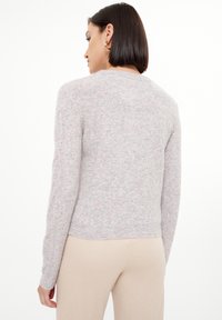 Maglione a maglia di un delicato rosa pallido, leggermente strutturato, con maniche lunghe, colletto a giro e orlo a costine. Tessuto morbido con leggere variazioni di colore.