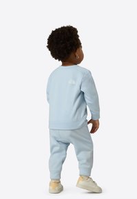 Light blue sweatshirt and matching joggers made of soft fabric, featuring a small white logo on the back and ribbed cuffs.