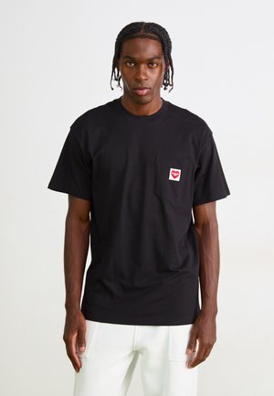 Black cotton t-shirt with a crew neck, short sleeves, and a red heart-shaped logo on the left chest pocket. Smooth texture.