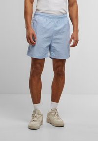 Shorts bleu clair en tissu léger, dotés d'une taille élastique, de poches latérales et d'une petite étiquette logo sur l'ourlet.