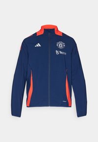Giacca sportiva blu con dettagli rossi, design con zip completa, caratterizzata dal logo del Manchester United e testo. Realizzata in materiale leggero.