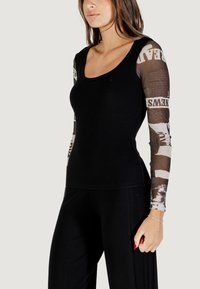 Schwarzes, geripptes Langarmshirt mit durchsichtigen, gemusterten Ärmeln im Zeitungsstil. Rundhalsausschnitt, slim fit und weicher Stoff.