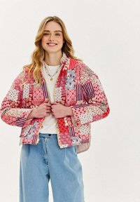 Prešívaná bunda so zložením z rôznych odtieňov ružovej, červenej a fialovej, so vzormi kvetov a pruhov a so zapínaním na zips.