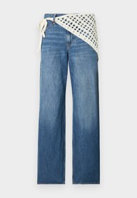 Μπλε τζιν παντελόν ι φαρδιάς γραμμής με λευκή λεπτομέρεια κρεπ πλεξίματος δεμένη στη μέση σε απλό φόντο.