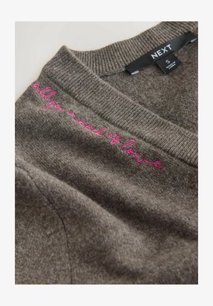 Grauer Pullover mit geripptem Kragen und pink gesticktem Text "all you need is love" auf der linken Seite. Weiche Textur und lässiges Design.
