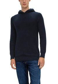 Marineblaue Kapuzensweatshirt mit gerippter Textur, figurbetontem Design und langen Ärmeln. Kombiniert mit dunklen Jeans, die einen lässigen Stil zeigen.