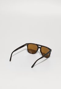 Ochelari de soare cu nuanțe maronii, cu ramă din într-o combinație de faină de țestoasă, având o formă rectangulară și brațe subțiri, elegante. Accente din hardware transparent pe laterale.