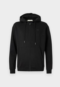 Svart zip-up hettegenser med frontlommer, justerbar snøring på hetten og diskret logo på venstre bryst mot en helt hvit bakgrunn.