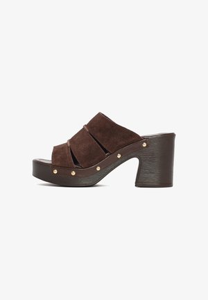 Bruine suède open-toe mule sandaal met blokhak, plateauzool en goudkleurige studs langs de zijkant.