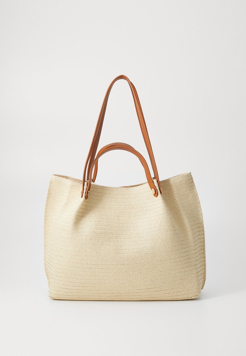 Borsa tote in paglia tessuta beige con due manici in pelle marrone, caratterizzata da un ampio apertura superiore e da un sottile motivo testurizzato sulla superficie.