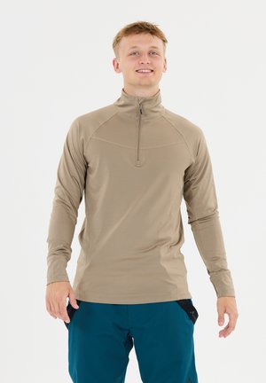 Beige lange mouwen pullover met een kwart rits, met raglanmouwen en platte naden. Gecombineerd met teal broek, wat zorgt voor een contrasterende look.