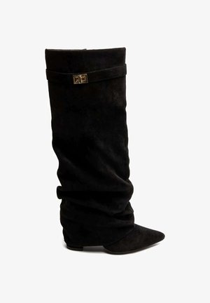 Botte noire en daim hauteur genou au design froncé, bout pointu, talon plat, et bride décorative avec boucle dorée près du haut.