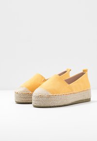 Gule espadrillos med en overdel i canvas, jute mellemsål og gummisål. Har en rund tå og syninger langs sålen.