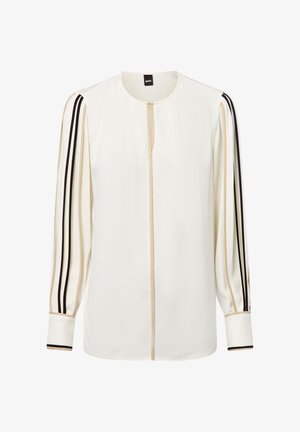 Witte blouse met lange mouwen met beige en zwarte strepen langs de mouwen en het midden, ronde halslijn en omgeslagen polsen.