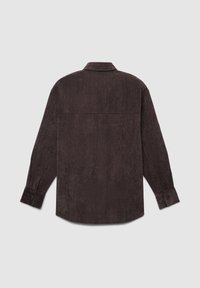 Braune Corduroy-Hemd mit langen Ärmeln, Kragen, Knopfmanschetten und einem Rückenträgerdesign. Die Textur ist weich und gerippt.