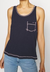 Marineblauw tanktop met een ronde halslijn, roze stiksel en een klein borstzakje. Gemaakt van zachte stof, ideaal voor casual kleding.