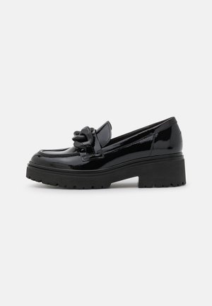 Sort laklæder chunky loafer med tyk sål og dekorativ stor kædedetalje på vampen, set fra siden på hvid baggrund.