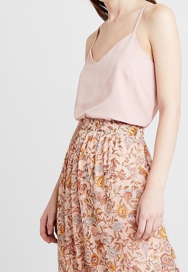 Světle růžový top na tenkých ramínkách v kombinaci s květinovou maxi sukni zdobenou vícbarevnými květinami na jemném broskvovém pozadí. Elastický pas.