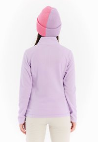 Lila fleece vest met een hoge kraag, zachte textuur en getailleerd ontwerp. Het model draagt een twee-kleurige gebreide muts in roze en paars.