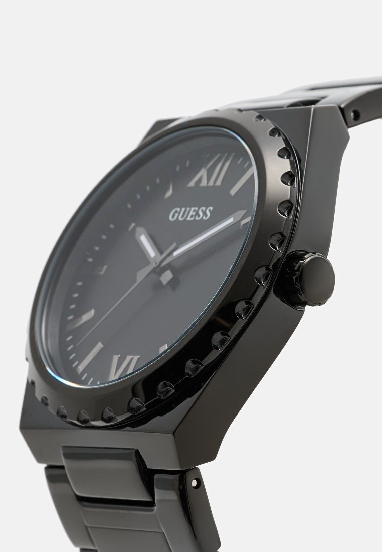 Czarny stalowy zegarek z okrągłą tarczą, znacznikami w postaci cyfr rzymskich i fakturowaną lunetą. Posiada wypolerowaną czarną bransoletę i wyraźną koronę.