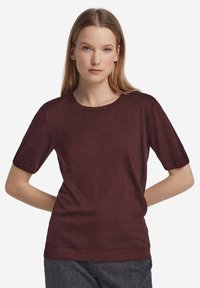 Burgundröd kortärmad tröja med rund halsringning, sl ät textur och uppvikta ärmslut. Klassisk figursydd design och ribbad fåll detalj.