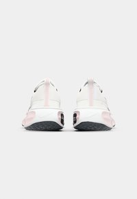 White athletic shoes with a sleek design and pink accents, featuring a textured sole and a cushioned heel for comfort.