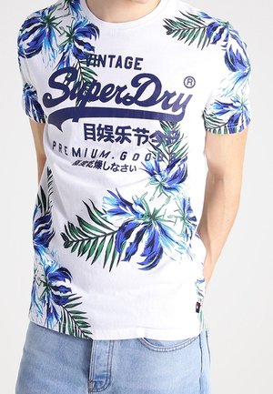 Weißes Baumwoll-T-Shirt mit blauem Blumen- und grünen Blattmustern. "SuperDry"-Logo in Dunkelblau quer über der Brust gedruckt. Kurze Ärmel.
