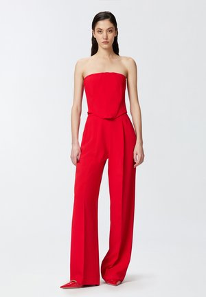 Mono rojo sin tirantes con un corsé ajustado, pantalones de pierna ancha y tejido suave y texturizado. Acentuado con costuras mínimas.