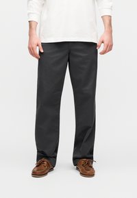 Γκρι βαμβακερό παντελόνι με ίσια γραμμή, με λεία υφή και διακριτική λάμψη. Συνδυασμένο με καφέ δερμάτινα παπούτσια.