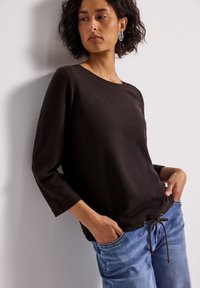 Ciemnobrązowy sweter o fakturowanej powierzchni, z rękawami do trzech czwartych i okrągłym dekoltem, z detalem w postaci sznureczka na dole.