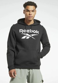 Sudadera negra de Reebok con bolsillo canguro frontal, capucha con cordón y gran logo blanco en el pecho. Tela suave y puños acanalados.