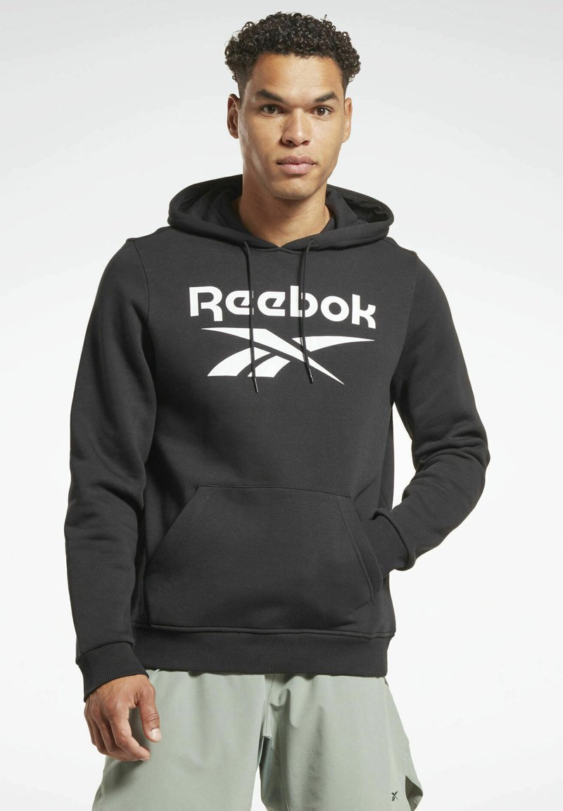 Sudadera negra de Reebok con bolsillo canguro frontal, capucha con cordón y gran logo blanco en el pecho. Tela suave y puños acanalados.