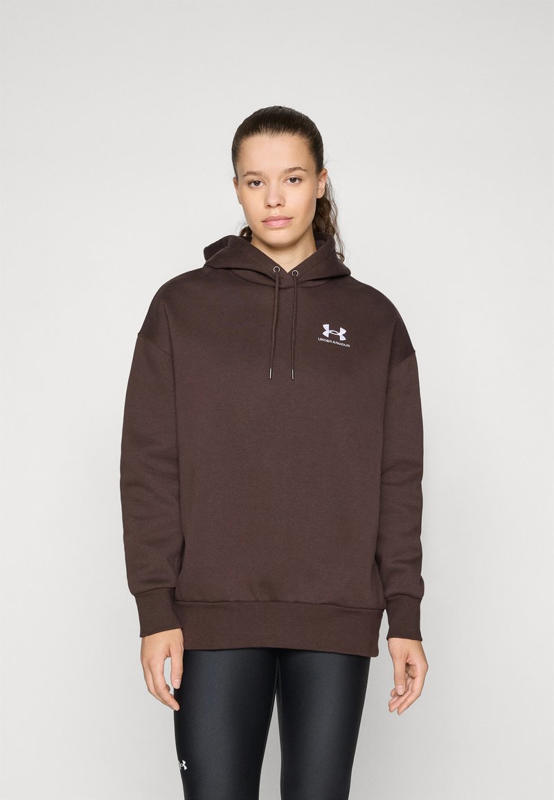 Brun hettegenser med en løs passform, frontlomme og hvit logo aksent. Sammen med svarte leggings med en glatt tekstur.