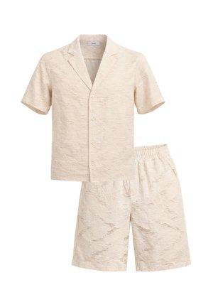 Camicia beige a maniche corte con bottoni e collo a risvolto abbinata a pantaloncini con vita elastica coordinati, adatta per un abbigliamento estivo casual.