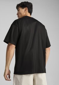 Sort t-shirt med korte ærmer i løstsiddende pasform, lavet af glat stof med subtile vertikale striber. Rund halsudskæring og syet kant.