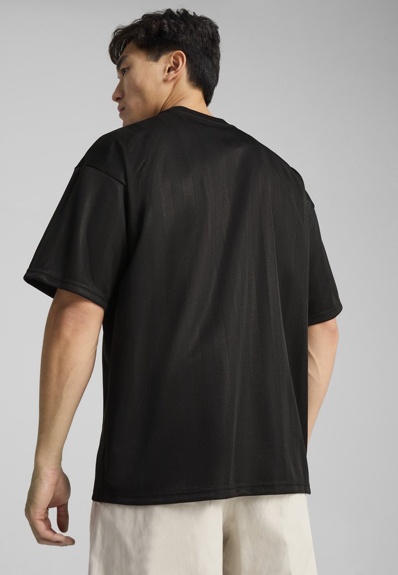 Sort t-shirt med korte ærmer i løstsiddende pasform, lavet af glat stof med subtile vertikale striber. Rund halsudskæring og syet kant.