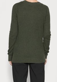 Dunkelgrüner Strickpullover mit strukturiertem Muster, langen Ärmeln und rundem Ausschnitt; endet unter der Hüfte mit einem geraden Schnitt.