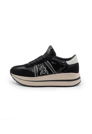 Sneaker bianca e nera con camoscio e tessuto lucido, suola beige spessa, lacci e logo sul lato su sfondo bianco.