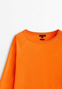 Oranges Baumwollsweatshirt mit Rundhalsausschnitt, gerippten Kanten und Raglanärmeln. Glatte Textur und keine sichtbaren Muster oder Akzente.