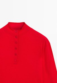 Maglia rossa a maniche lunghe con collo alto, arricchita da sei bottoni sul davanti, realizzata in un tessuto lavorato a maglia liscio.