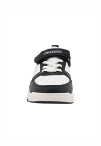 Baskets noir et blanc avec une tige en cuir texturé, des perforations pour la respirabilité, un laçage à l'avant et une sangle Velcro pour un maintien sécurisé.