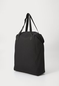 Borsa a tracolla nera con doppie maniglie piatte, realizzata in tessuto resistente. Presenta una forma quadrata e un design minimalista senza hardware visibile.