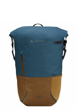 Zaino blu e marrone con design a rotolo, parte superiore texturizzata, sezione inferiore morbida di colore marrone e tasca laterale con cerniera. Logo Vaude sulla parte anteriore.