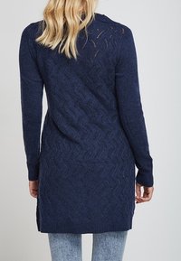 Navy blue knit cardigan with a hood, featuring a wave-pattern texture, long sleeves, and side slits at the hem.