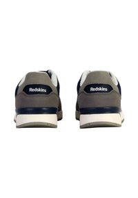 Baskets de sport grises et bleu marine avec un dessus en daim et textile, accents blancs et logo "Redskins" sur le talon, avec une semelle en caoutchouc.