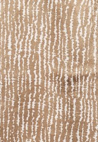 Tissu texturé présentant un motif abstrait répétitif dans des teintes de marron et de crème, évoquant l'apparence du grain du bois.