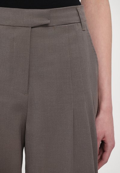 Braune maßgeschneiderte Hosen mit flachem Frontdesign, einem einzelnen Falz und seitlichen Taschen. Der Stoff ist glatt mit subtilen Nähdetails.